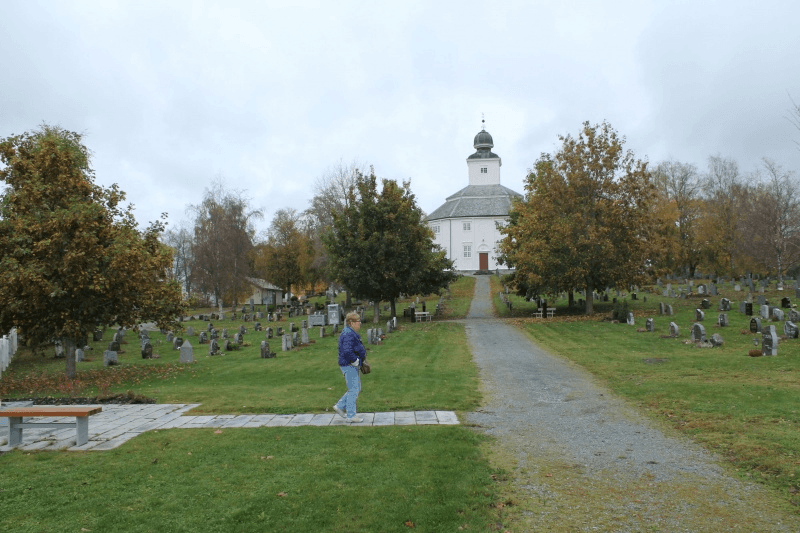 Klæbu kirkegård i høstfarger, med Klæbu kirke i bakgrunnen.